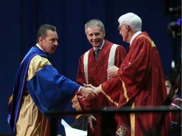 FCA Canada CEO Reid Bigland, left, is congratulated by University of Windsor chancellor Ed Lumley, right,  and University of Windsor president and Alan Wildeman after  Bigland received an honorary doctor of laws degree during the fall University of Windsor convocation on October 17, 2015.