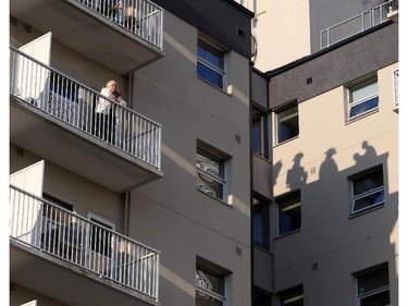 Shadows of firefighters can be seen as a woman stands on a balcony following an  early morning apartment fire at 2455 Rivard in Windsor, Ontario on October 7, 2015.   (JASON KRYK/The Windsor Star)