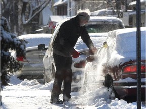 A motorist clears snow off his car after a snow storm.