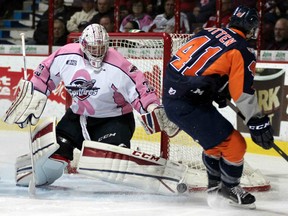 Spits goaltender Garret Hughson, left, makes a save on Flint's Will Bitten at the WFCU Centre. (Tim Cornett/windsorspitfires.com)