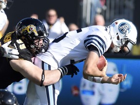Windsor's Michael Atkinson, left, tackles Toronto quarterback Ricky Ray (15) during first half of the CFL Eastern Division Semifinal Sunday in Hamilton.