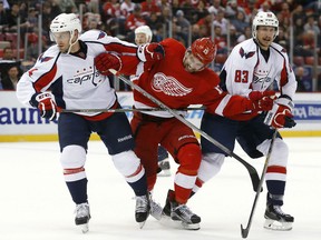 Detroit Red Wings center Riley Sheahan (15) skates through Washington Capitals defenseman Taylor Chorney (4) and Jay Beagle (83) in the second period of an NHL hockey game, Wednesday, Nov. 18, 2015 in Detroit. (AP Photo/Paul Sancya)