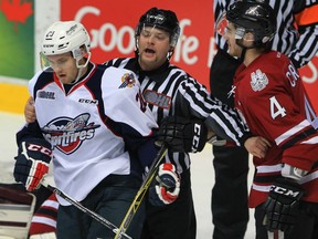 A linesman breaks up Windsor Spitfires Andrew Burns, left, and Guelph Storm Noah Carroll in OHL action from WFCU Centre November 19, 2015. Spits Mikhail Sergachev was assessed a penalty on the play.