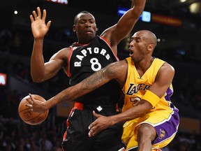 Kobe Bryant (24) of the Los Angeles Lakers passes around Toronto Raptors Bismack Biyombo (8) under the Lakers basket during their NBA match up, November 20, 2015 at Staples Center in Los Angeles, California. AFP PHOTO/ ROBYN BECKROBYN BECK/AFP/Getty Images
