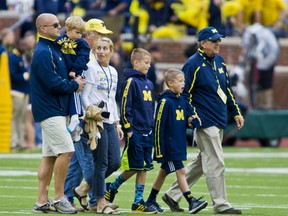 In this Sept. 12, 2015, file photo, former Michigan coach Lloyd Carr, far right, leads his grandsons T.J. and Tommy Carr, daughter-in-law Tammi Carr, and son Jason Carr, far left, holding his son Chad Carr, onto the Michigan Stadium field for the pregame coin toss, before an NCAA college football game against Oregon State in Ann Arbor, Mich. The 5-year-old grandson of former Michigan football coach Lloyd Carr has died more than a year after he was diagnosed with a rare, inoperable form of brain cancer. Chad Carr’s father, Jason Carr, says his son died Monday, Nov. 23, 2015, in the family’s Pittsfield Township home, where the boy had recently entered hospice care.  (AP Photo/Tony Ding, File)