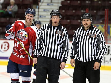 OHL linesman Ryan Lachine of Windsor, right, skates with linesman Geoff Rutherford in OHL game between Windsor Spitfires and Saginaw Spirit Nov. 27, 2015.  Saginaw's Will Petschenig, left, joins the photo with a smile.  Lachine is calling it a career after 15 years and was honoured before the OHL game at WFCU.