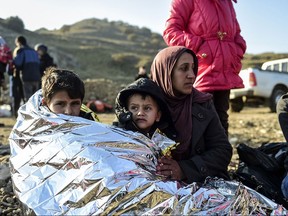 A Syrian family waits after arriving on the Greek island of Lesbos along with other migrants and refugees, on November 17, 2015, after crossing the Aegean Sea from Turkey.