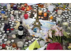 Candles, a bottle of wine, flowers and a replica of the Eiffel Tower are pictured outside the Petit Cambodge restaurant, a site of last Friday's attacks, in Paris, Tuesday, Nov. 17, 2015. France made an unprecedented demand on Tuesday for its European Union allies to support its military action against the Islamic State group as it launched new airstrikes on the militants' Syrian stronghold, days after attacks in Paris linked to the group killed at least 129 people.