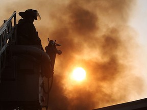Sun shines through smoke billowing from a roof as firefighters battle a blaze on the 1000 block of Albert Road in Windsor, Ont., in this file photo.