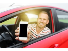 Man in car showing smart phone. Photo by fotolia.com.