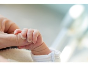 Newborn baby touching his mother's hand. Photo by fotolia.com.