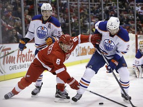 Detroit Red Wings left winger Justin Abdelkader (8) reaches for the puck next to Edmonton Oilers defenceman Andrej Sekera (2) during the second period of an NHL hockey game, Friday, Nov. 27, 2015, in Detroit.