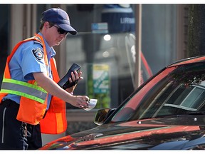 In this file photo, a municipal bylaw enforcement officer from Commissionaires issues a parking ticket on Wyandotte Street east in Windsor, Ont., Tuesday, July 19, 2011.   (DAX MELMER / The Windsor Star)