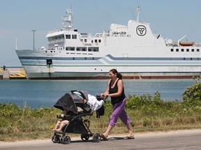 A woman walks her baby along the shoreline on Pelee Island, Ont. in this file photo as the Jiimaan ferry sits on the dock in the background.