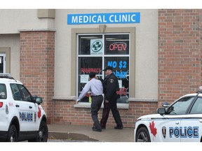 A Windsor Police officer speaks with a witness at the scene of an armed robbery at the Totten Pharmacy on Tuesday, November 10, 2015 in Windsor, ON.
