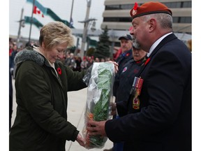 Theresa Charbonneau, left, who lost her son Cpl. Andrew Grenon while serving with the Canadian Army in Afghanistan in 2008, passes a ceremonial wreath to Brad Saunders, a retired airman with the Royal Canadian Air Force, during the Remembrance Day ceremony at the cenotaph in downtown Windsor, Monday, Nov. 11, 2013.