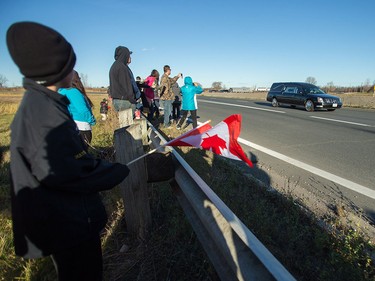 The hearse carrying the body of former Canadian soldier John Gallagher, who was killed while fighting against ISIS in Syria, passes by London, Ontario, Friday, November 20, 2015 where hundreds lined overpasses to pay their respects.