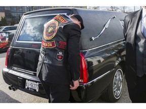 A veteran puts his hand on the hearse carrying the casket of John Gallagher during his repatriation ceremony in Toronto on November 20, 2015.