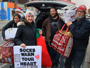 Sarah Lewis, centre, is welcomed by Street Help visitors Melanie Smith, left, Steve Wait, right, and others with generous gifts including over $16,000 in cash for Street Help Homeless Centre on Thursday, Dec. 17, 2015. In addition, Lewis brought 4,000 pairs of socks, and dozens of pies and hams.