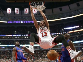 Chicago Bulls center Joakim Noah (13) dunks between Detroit Pistons guard Reggie Jackson (1) and Anthony Tolliver (43) during the first half of an NBA basketball game Friday, Dec. 18, 2015, in Chicago. (AP Photo/Charles Rex Arbogast)