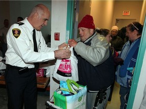 Hundreds of area needy line up for the annual Mikhail turkey and food giveaway, this year at 301 Ouellette Avenue December 21, 2012. In photo, Windsor Police Chief Al Frederick helps Brian Parrish with his load of groceries including a young turkey. (NICK BRANCACCIO/The Windsor Star)
