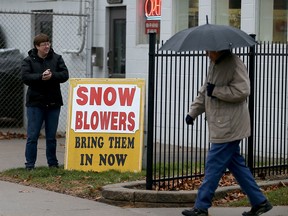 Kim Ducharme, left, of Seguins Hardware on Girardot Street in Windsor displays a snowblower repair sign on Monday, Dec. 21, 2015.  Very mild temperatures have kept snowblowers locked away.
