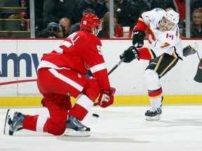 T.J. Brodie #7 of the Calgary Flames shoots the puck past a defending Niklas Kronwall #55 of the Detroit Red Wings during their NHL game at Joe Louis Arena on November 23, 2011 in Detroit, Michigan.