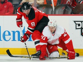 Jiri Tlusty #9 of the New Jersey Devils and Alexei Marchenko #47 of the Detroit Red Wings battle for the puck during the second period at the Prudential Center on December 11, 2015 in Newark, New Jersey.  (Photo by Bruce Bennett/Getty Images)