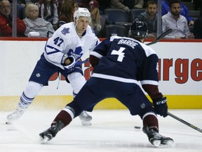 Toronto Maple Leafs center Leo Komarov, back, of Estonia, pursues the puck as Colorado Avalanche defenseman Tyson Barrie watches during the second period of an NHL hockey game Monday, Dec. 21, 2015, in Denver. (AP Photo/David Zalubowski)