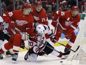 New Jersey Devils' Lee Stempniak (20) tries to maintain control of the puck against Detroit Red Wings' Danny DeKeyser (65), Dylan Larkin (71) and Niklas Kronwall (55), of Sweden, during the first period of an NHL hockey game at Joe Louis Arena Tuesday, Dec. 22, 2015, in Detroit. (AP Photo/Duane Burleson)