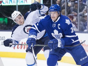 Winnipeg Jets' Adam Lowry, left, and Toronto Maple Leafs' Dion Phaneuf fight for position during first period NHL hockey action, in Toronto, on Wednesday, Nov. 4, 2015. THE CANADIAN PRESS/Darren Calabrese