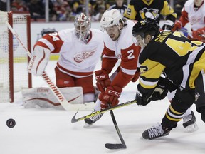 Pittsburgh Penguins left wing Conor Sheary (43) and Detroit Red Wings defenseman Brendan Smith (2) reach for the puck during the first period of an NHL hockey game, Thursday, Dec. 31, 2015, in Detroit. (AP Photo/Carlos Osorio)