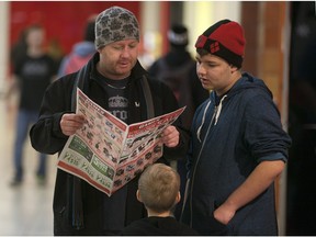 John Sewell and his sons, Kaden Sewell, 14, and Zack Sewell, 7, look through a flyer while shopping at Devonshire Mall on Boxing Day, Saturday, Dec. 26, 2015.