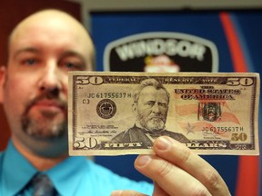 Const. Rob Durling of the Financial Crimes Unit displays counterfeit U.S. currency seized in Windsor, Ont. $10,000 in fake bills were found in a Walkerville alley this week.