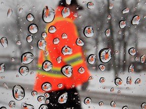A person wearing a safety vest is seen through water droplets during a period of freezing rain along Howard Avenue in Windsor on Feb. 8, 2013.