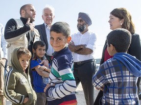 Young Syrian refugees gather around Minister of Immigration, Refugees and Citizenship John McCallum, second from left, Defence Minister Harjit Sajjan and Health Minister Jane Philpott, right, as they tour the Zaatari Refugee Camp, near the city of Mafraq, Jordan, on Sunday, Nov. 29, 2015.