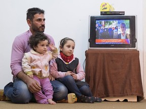 Syrian Refugee Samer Albqerat from Tal Shehab, Syria sits with his daughters Goly, nine months, and Nada, 6 on Tuesday, December 1, 2015 in Irbid, Jordan. The family is waiting for approval to immigrate to Canada.