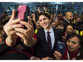 Canadian Prime Minister Justin Trudeau poses for selfies with workers before he greets refugees from Syria at Pearson International airport, in Toronto, on Thursday, Dec. 10, 2015.