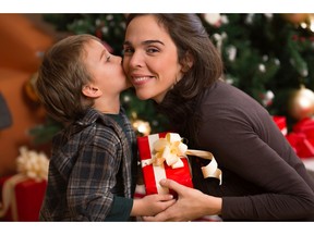 Little boy kissing his mother and giving her a Christmas present. Photo by fotolia.com.