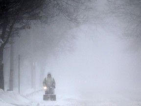 A resident clears snow from the road with a snowblower in the 1900 block of Pillette Road. Jan. 2, 2015.