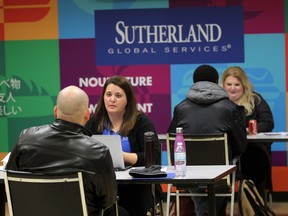 Job seekers at Sutherland Global Services speaks with representatives from the company on Wednesday, Dec. 9, 2015, during a job fair at the Ouellette Avenue business.
