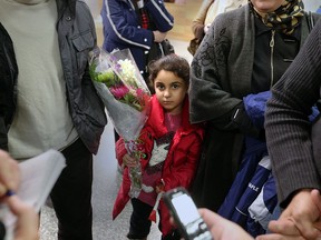 Syrian refugee Aya Alhajjeh, 6, holds a Canadian flag and flowers after arriving into Windsor International Airport with her family on Dec. 21, 2015.