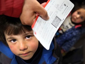 Abdulhameed Al-Shahmeh, 6, left, and his sister Salam, 4, look up as their father Saoud Al-Shahmeh displays their plane tickets to media after the Syrian Refugees arrived at Windsor Airport on Dec. 29, 2015 in Windsor, Ont.