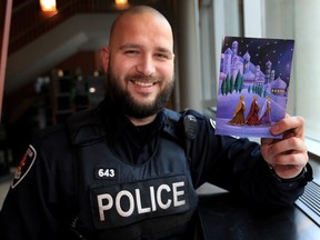 Windsor police Const. L. J. Kovacevic holds a Christmas card December 5, 2015 sent by a local woman named Judy, who has sent out hundreds of cards over the years to military, firefighters and law enforcement. (NICK BRANCACCIO/Windsor Star)