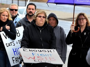 Injured worker Liz Garant, centre, was joined by MP Tracey Ramsey, right, and about 20 others including Brian Hogan, president Windsor District Labour Council, during a morning rally in support of injured workers at WSIB offices on Ouellette Avenue, Monday, Dec. 14, 2015.
