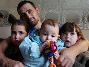 Ibrahim Tonbari holds three of his four children - Noura, 7,  Hilal, seven months, and  Blal, 6 - at their Windsor home on Dec. 22, 2015.