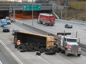 OPP and towing operators arrive to assist with the clean up after a scrap hauler carrying automobile motors overturned on westbound Herb Gray Parkway 401, December 22, 2015. Traffic was re-routed until the mess was cleared up.