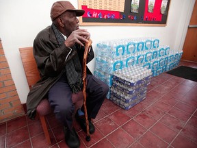 A man sits next to a stack of bottled water at a rally where the Rev. Jesse Jackson spoke about the water crises at the Heavenly Host Baptist Church January 17, 2016 in Flint, Michigan. U.S. President Barack Obama declared a federal emergency in Michigan, which will free up federal aid to help the city of Flint with lead contaminated drinking water. Michigan Gov. Rick Snyder requested emergency and disaster declarations after activating the National Guard to help the American Red Cross distribute water to residents. (Photo by Bill Pugliano/Getty Images)