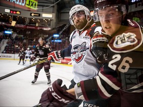 Bradley Latour #63 of the Windsor Spitfires drives a hit against forward Josh Coyle #26 of the Peterborough Petes on October 8, 2015 at the WFCU Centre in Windsor, Ontario, Canada.
