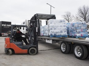 Concessions and maintenance manager Mika Roots helps remove pallets of water from a truck. Approximately 55,000 water bottles are delivered to the Dort Federal Credit Union Event Center on Saturday Jan. 23, 2016 in Flint, Mich.